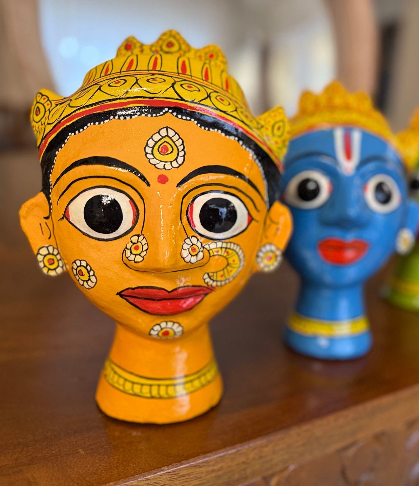 Colorful cherial busts with decorative patterns on a a mask made with tamarind past and wood husk