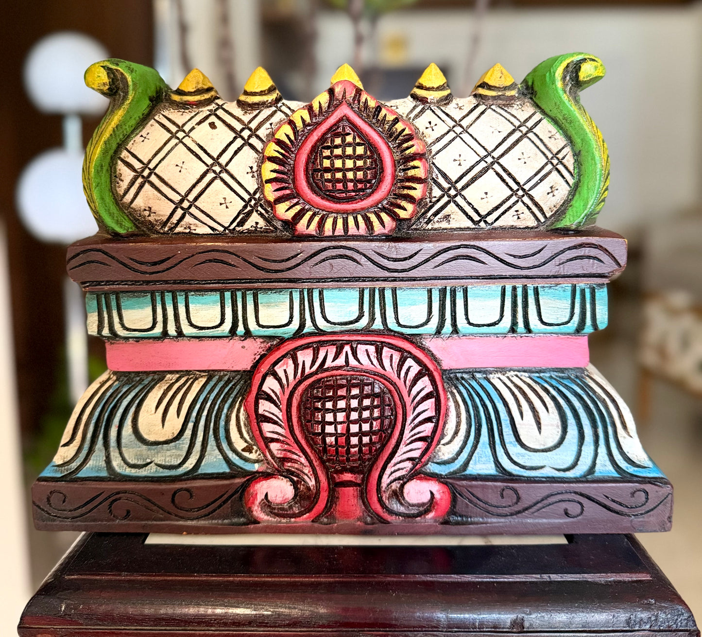 Decorative wooden gopuram with intricate carvings on a blurred background