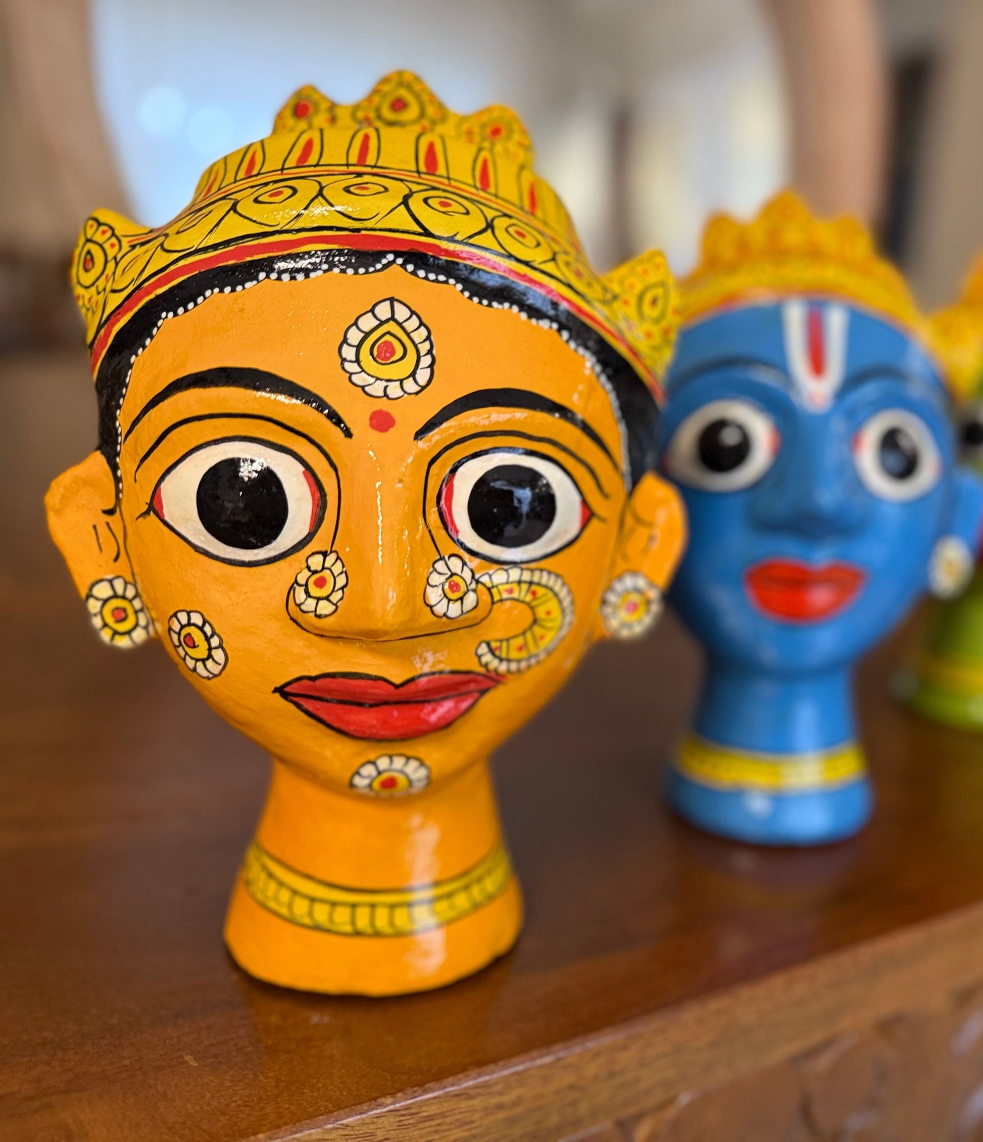 Colorful cherial busts with decorative patterns on a a mask made with tamarind past and wood husk